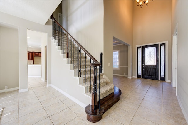 tiled foyer entrance with a towering ceiling and a chandelier