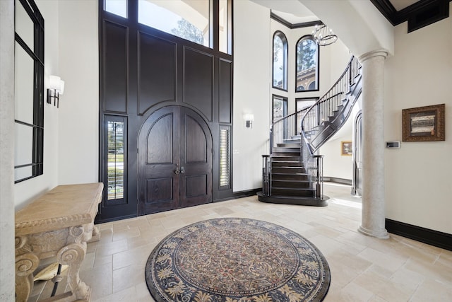 foyer with crown molding, a healthy amount of sunlight, a high ceiling, and decorative columns