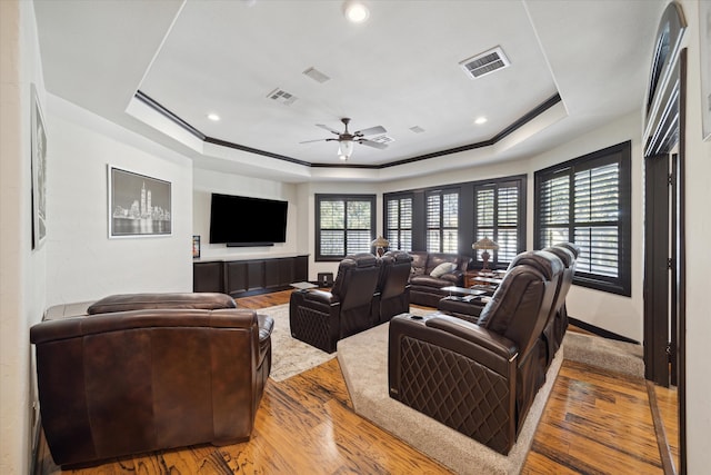 living room with ceiling fan, wood-type flooring, and a raised ceiling