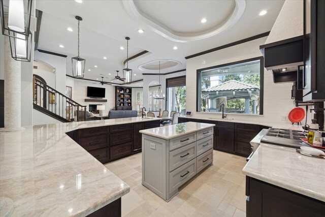 kitchen featuring decorative light fixtures, a tray ceiling, a large island, and plenty of natural light