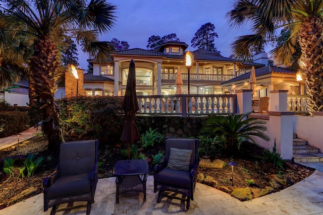 back house at dusk featuring a balcony