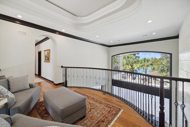 corridor with light hardwood / wood-style flooring, crown molding, and a tray ceiling