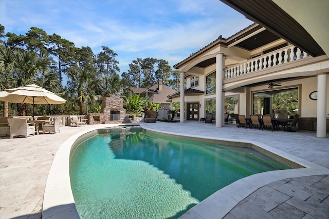 view of swimming pool featuring an outdoor stone fireplace and a patio area