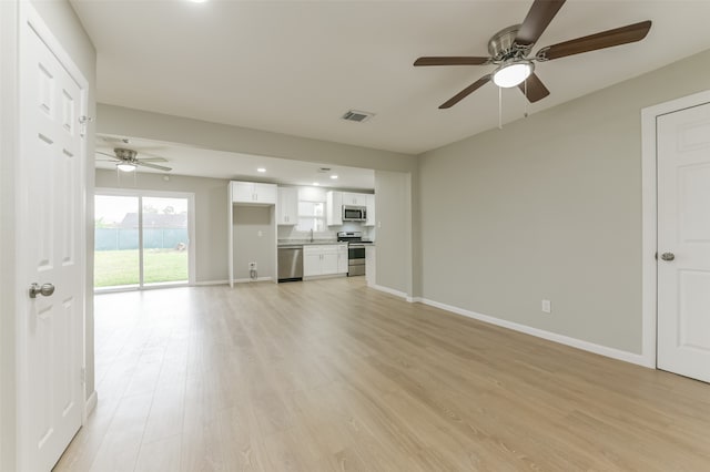 unfurnished living room with light wood-type flooring, sink, and ceiling fan