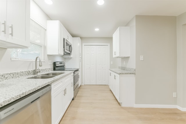 kitchen featuring white cabinets, stainless steel appliances, sink, and light hardwood / wood-style flooring