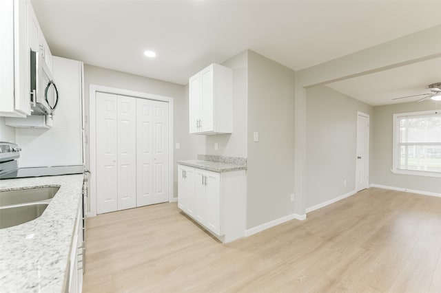 kitchen featuring white cabinetry, light stone countertops, sink, ceiling fan, and light hardwood / wood-style flooring