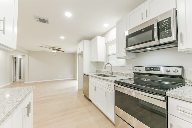 kitchen with stainless steel appliances, light hardwood / wood-style floors, sink, light stone countertops, and white cabinets