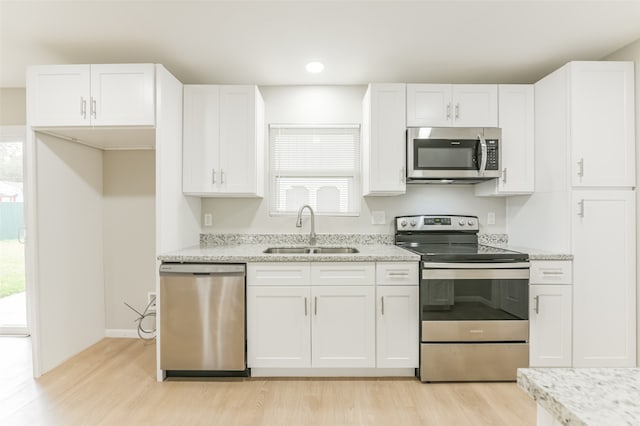 kitchen with light wood-type flooring, white cabinets, sink, and stainless steel appliances