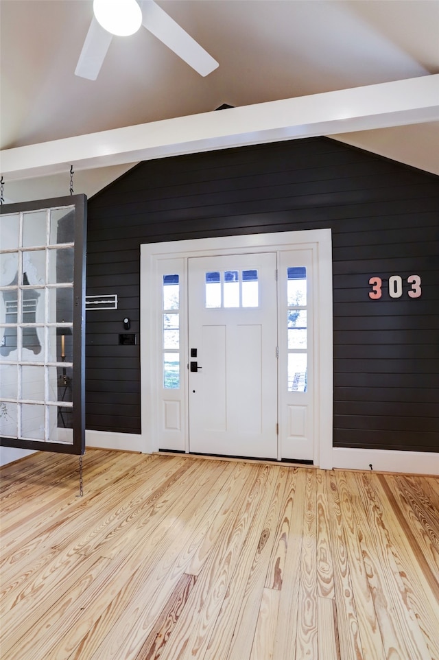 entrance foyer featuring a wealth of natural light, wooden walls, light hardwood / wood-style floors, and vaulted ceiling