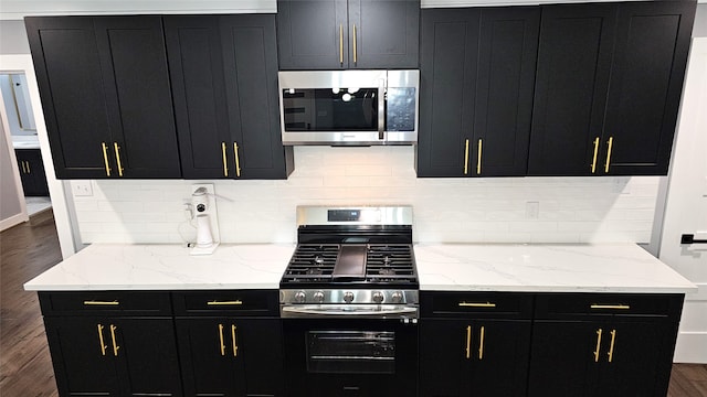 kitchen with decorative backsplash, stainless steel appliances, dark hardwood / wood-style floors, and light stone counters