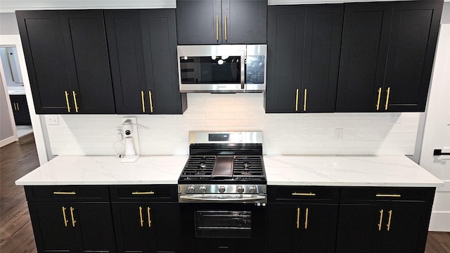 4526 Dixie Dr, Houston, TX 77021 - kitchen with appliances with stainless steel finishes, dark cabinetry, decorative backsplash, dark wood-style floors, and light stone counters