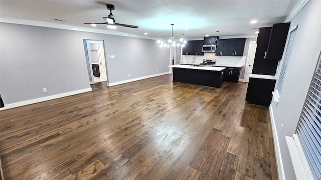 kitchen featuring stainless steel appliances, dark hardwood / wood-style flooring, a center island with sink, crown molding, and decorative light fixtures