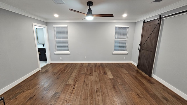 unfurnished bedroom with dark wood-type flooring, ornamental molding, a barn door, and ceiling fan