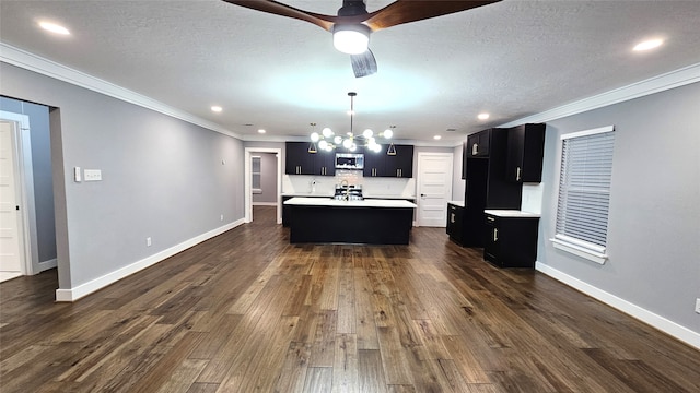 kitchen with dark hardwood / wood-style floors, a textured ceiling, a kitchen island with sink, and crown molding