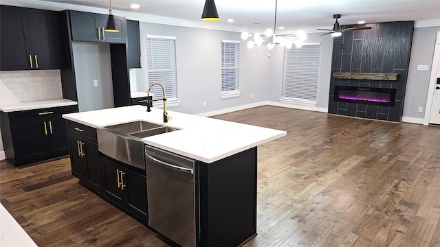 kitchen with tasteful backsplash, a fireplace, pendant lighting, an island with sink, and stainless steel dishwasher