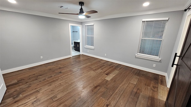 empty room with a barn door, crown molding, and hardwood / wood-style floors