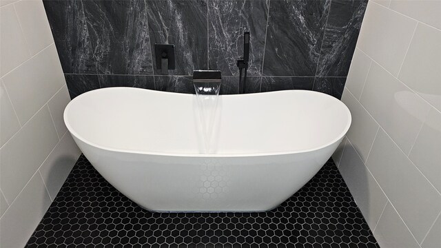 bathroom with a washtub, tile walls, and tile patterned flooring