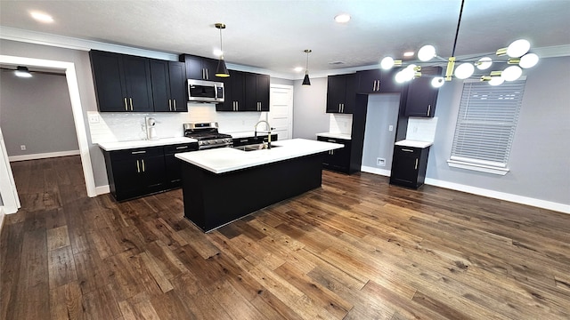 kitchen with hanging light fixtures, tasteful backsplash, an island with sink, crown molding, and appliances with stainless steel finishes