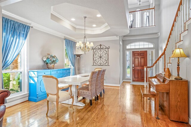 dining room with an inviting chandelier, crown molding, a tray ceiling, and light hardwood / wood-style flooring