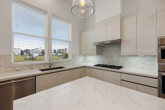 kitchen featuring light stone countertops, decorative backsplash, light brown cabinets, and stainless steel appliances