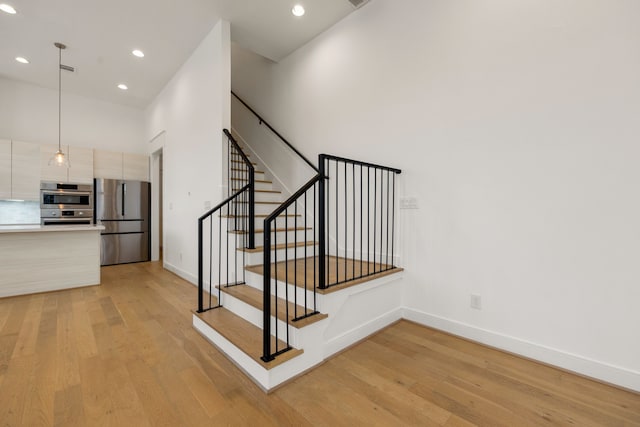 stairs featuring a towering ceiling and wood-type flooring