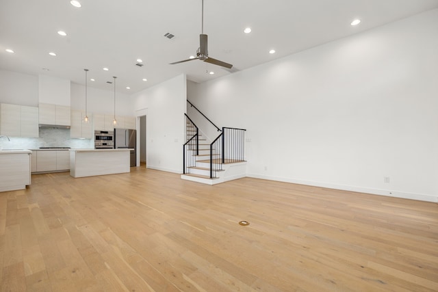 unfurnished living room featuring ceiling fan, sink, and light hardwood / wood-style floors