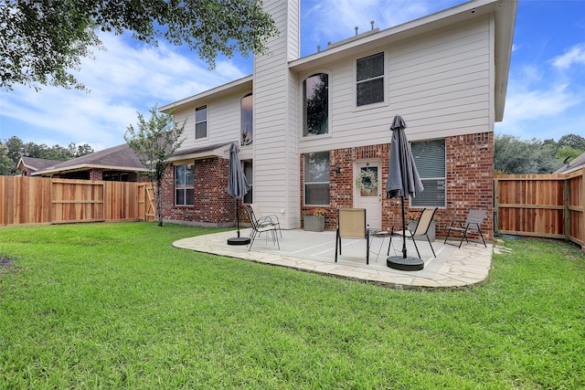 back of house featuring a lawn and a patio