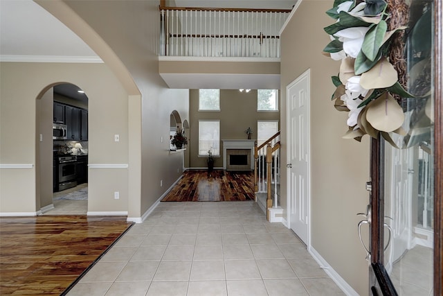 entrance foyer featuring a high ceiling, light hardwood / wood-style flooring, and crown molding