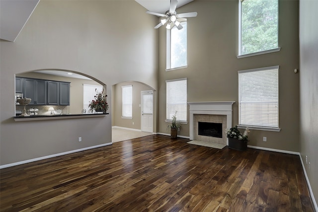 unfurnished living room featuring a towering ceiling, plenty of natural light, and dark hardwood / wood-style floors