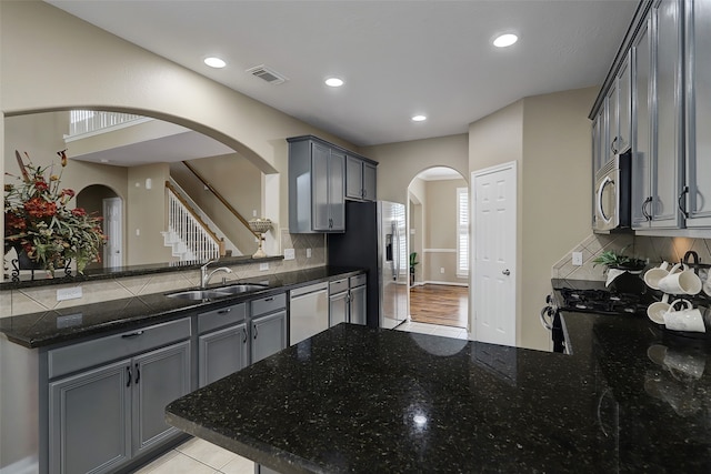 kitchen with tasteful backsplash, appliances with stainless steel finishes, gray cabinets, sink, and kitchen peninsula