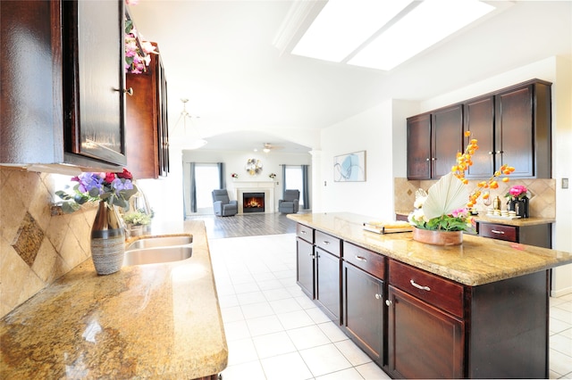 kitchen with decorative backsplash, light hardwood / wood-style floors, a center island, and light stone countertops