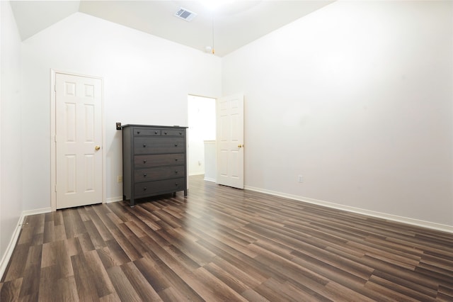 spare room featuring dark wood-type flooring and high vaulted ceiling