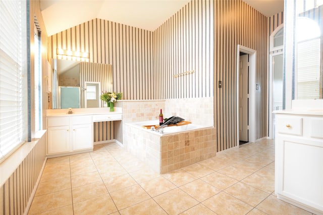 bathroom with tiled bath, tile patterned floors, vanity, a healthy amount of sunlight, and lofted ceiling