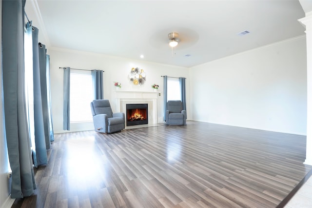 unfurnished living room featuring ceiling fan, wood-type flooring, crown molding, and decorative columns