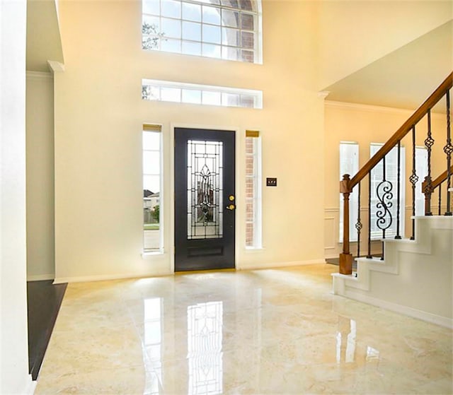 entryway featuring a towering ceiling and crown molding