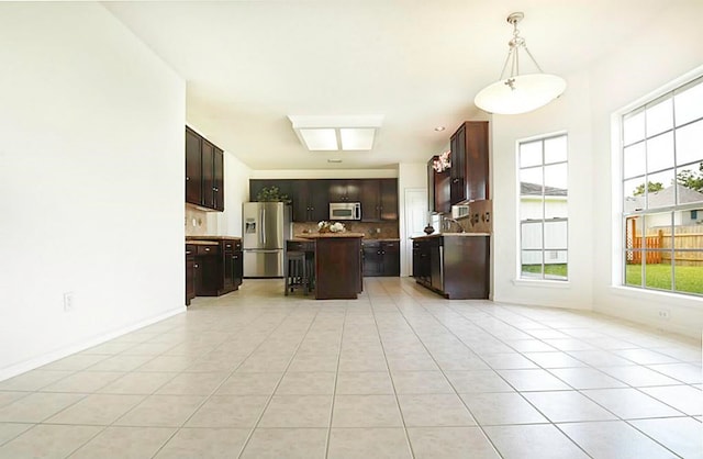 kitchen with stainless steel appliances, light tile patterned flooring, hanging light fixtures, and a center island