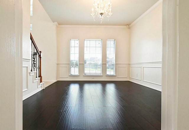 spare room featuring dark hardwood / wood-style flooring, a chandelier, and ornamental molding