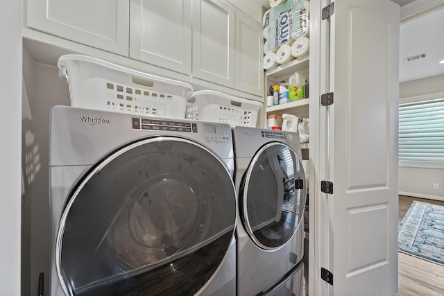 washroom with cabinets, washer and dryer, and light hardwood / wood-style flooring