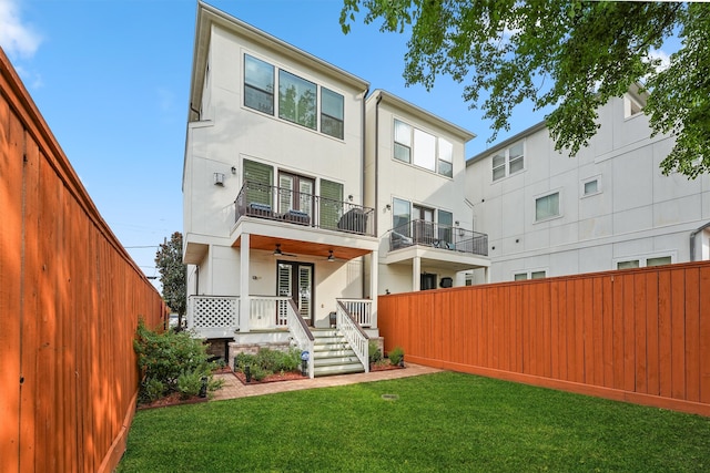 back of house featuring ceiling fan, a balcony, and a yard