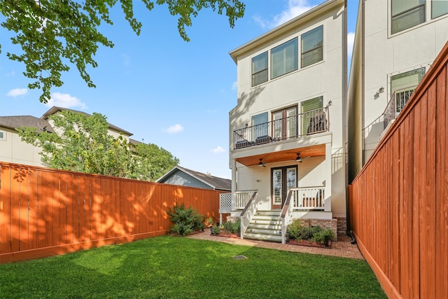 rear view of house featuring a lawn, ceiling fan, and a balcony