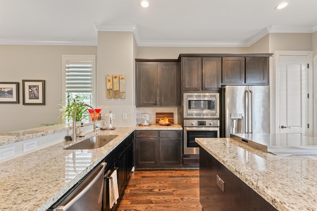 kitchen featuring stainless steel appliances, crown molding, dark brown cabinetry, and light stone counters