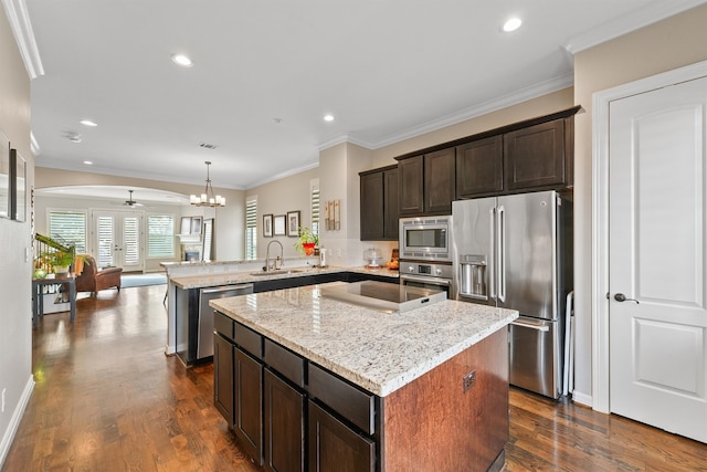 kitchen with dark wood-type flooring, kitchen peninsula, appliances with stainless steel finishes, and a center island