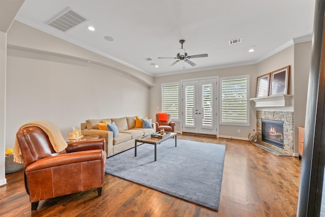 living room with ceiling fan, wood-type flooring, ornamental molding, and a fireplace