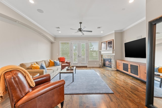 living room with a fireplace, wood-type flooring, ceiling fan, and crown molding