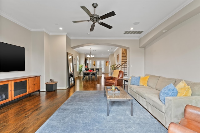 living room with ornamental molding, ceiling fan with notable chandelier, and dark wood-type flooring