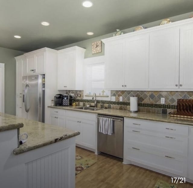 kitchen with white cabinets, appliances with stainless steel finishes, wood-type flooring, and sink