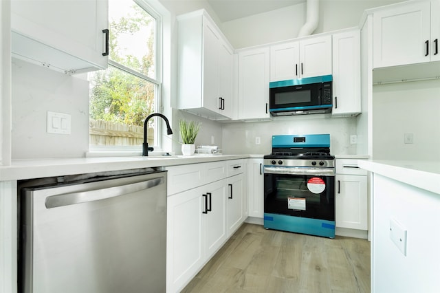 kitchen with stainless steel appliances, light hardwood / wood-style floors, white cabinetry, and backsplash