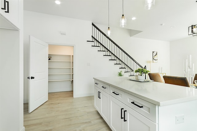 bar with white cabinets, pendant lighting, and light hardwood / wood-style flooring