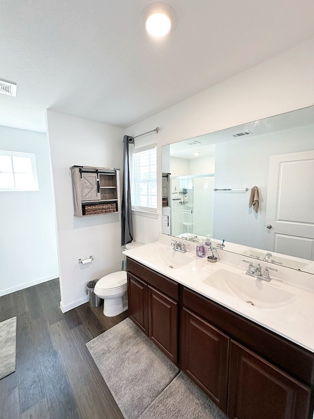 bathroom with hardwood / wood-style floors, vanity, toilet, and a shower with door