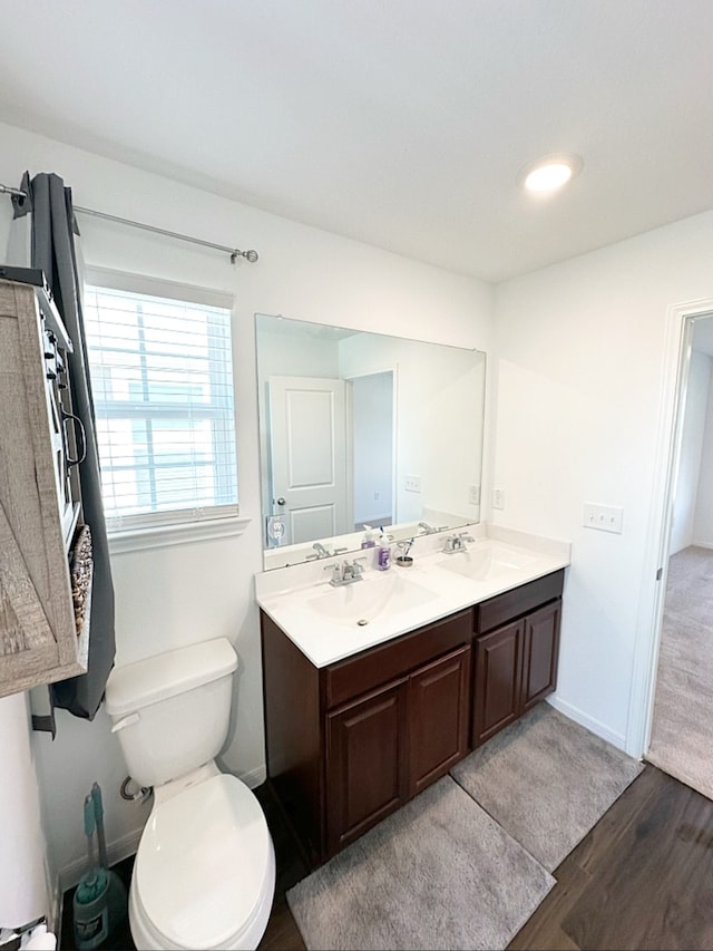 bathroom with toilet, vanity, and hardwood / wood-style flooring